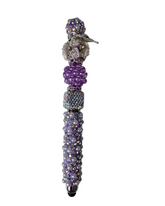 Decorative pen with purple beads and gemstones on a white background